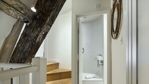 Eine Treppe führt zu einem Badezimmer mit einem weißen Waschbecken und einem Handtuch auf dem Boden.