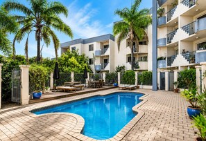 A swimming pool area with lounge chairs and a brick patio.