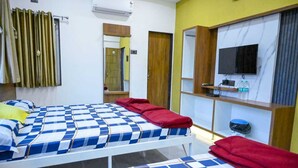 A hotel room with two beds, a TV, a shelf with toiletries, and a mirror. - hari krupa bhakta niwas (Jejuri)