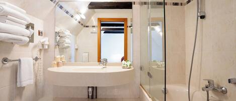 A bathroom with a sink, mirror, and shower.