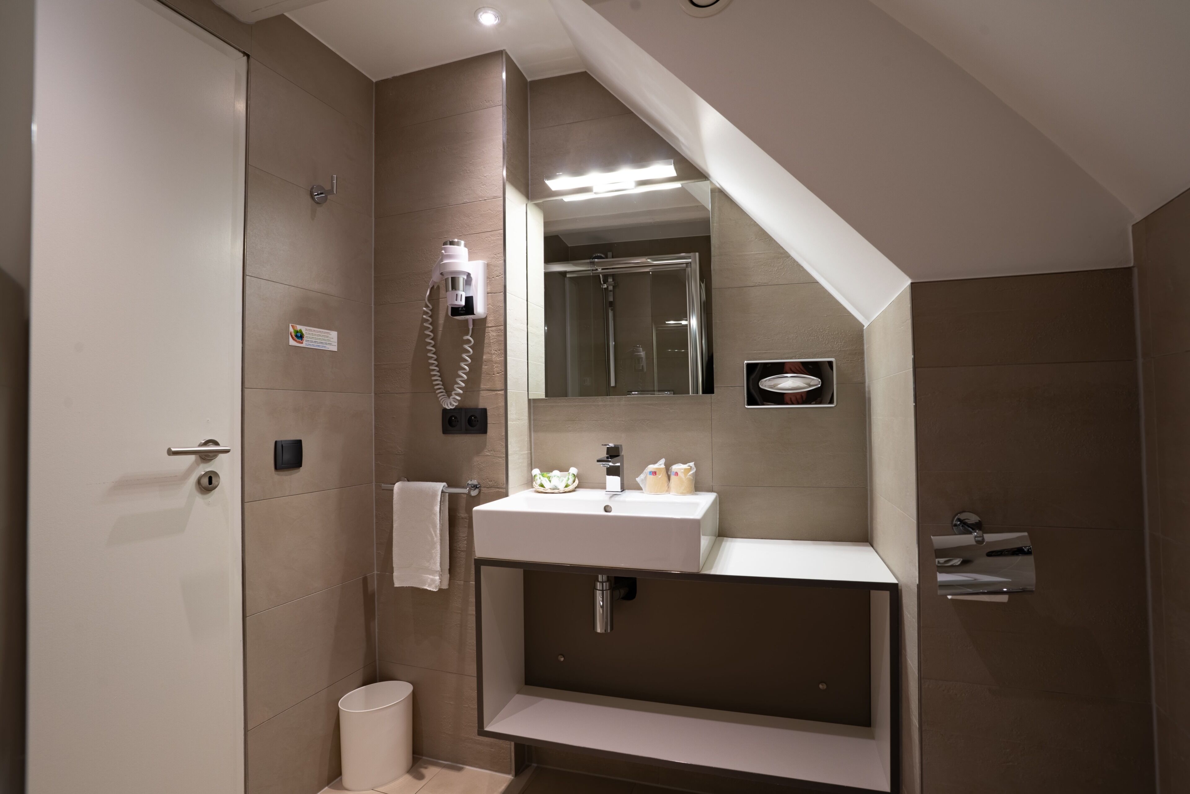 Une salle de bain moderne équipée d’une douche, d’un lavabo et d’un miroir.