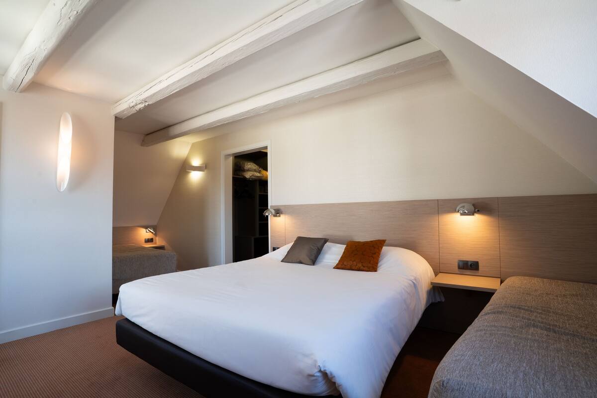 Una habitación de hotel moderna con una cama grande, mesitas de noche y un armario empotrado.