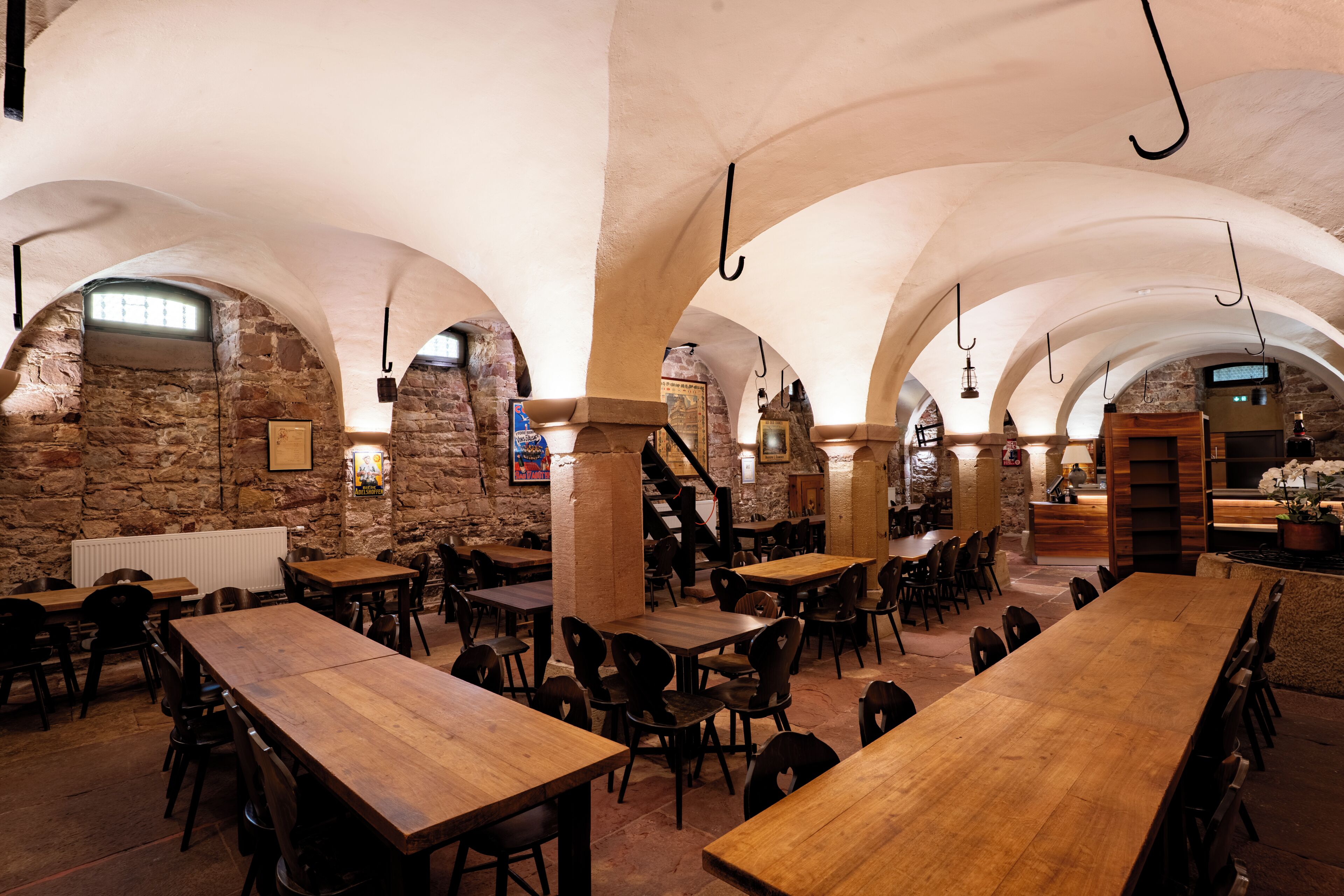 Un amplio comedor con techos altos en arco y paredes de piedra, con varias mesas y sillas de madera.