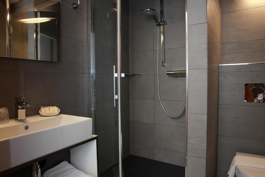Un baño moderno con cabina de ducha de vidrio, un lavabo blanco y un espejo.