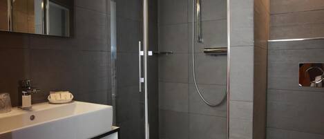 A modern bathroom with a glass shower enclosure, a white sink, and a mirror.