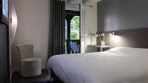 A hotel room with a bed, a chair, a small table with a plant, and a view of the outdoors. - Hôtel Restaurant Père Benoît (Entzheim)