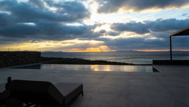 Area piscina con vista sul mare e sulle montagne al tramonto.