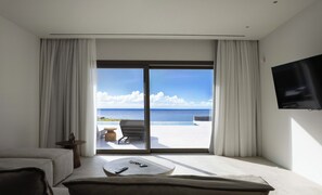 A modern room with a large sliding glass door leading to a balcony with a pool and ocean view. - Luxury Mykonos Villa with Private Pool and Stunning Sea Views (MYKONOS)