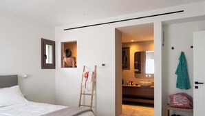 Una camera da letto con un letto, una scala, un bagno con un lavandino e un porta scarpe.