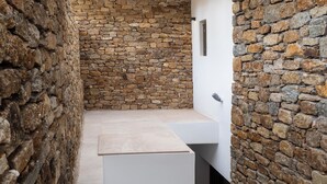 Un interno con pareti in pietra, un lavabo bianco moderno e un bancone.