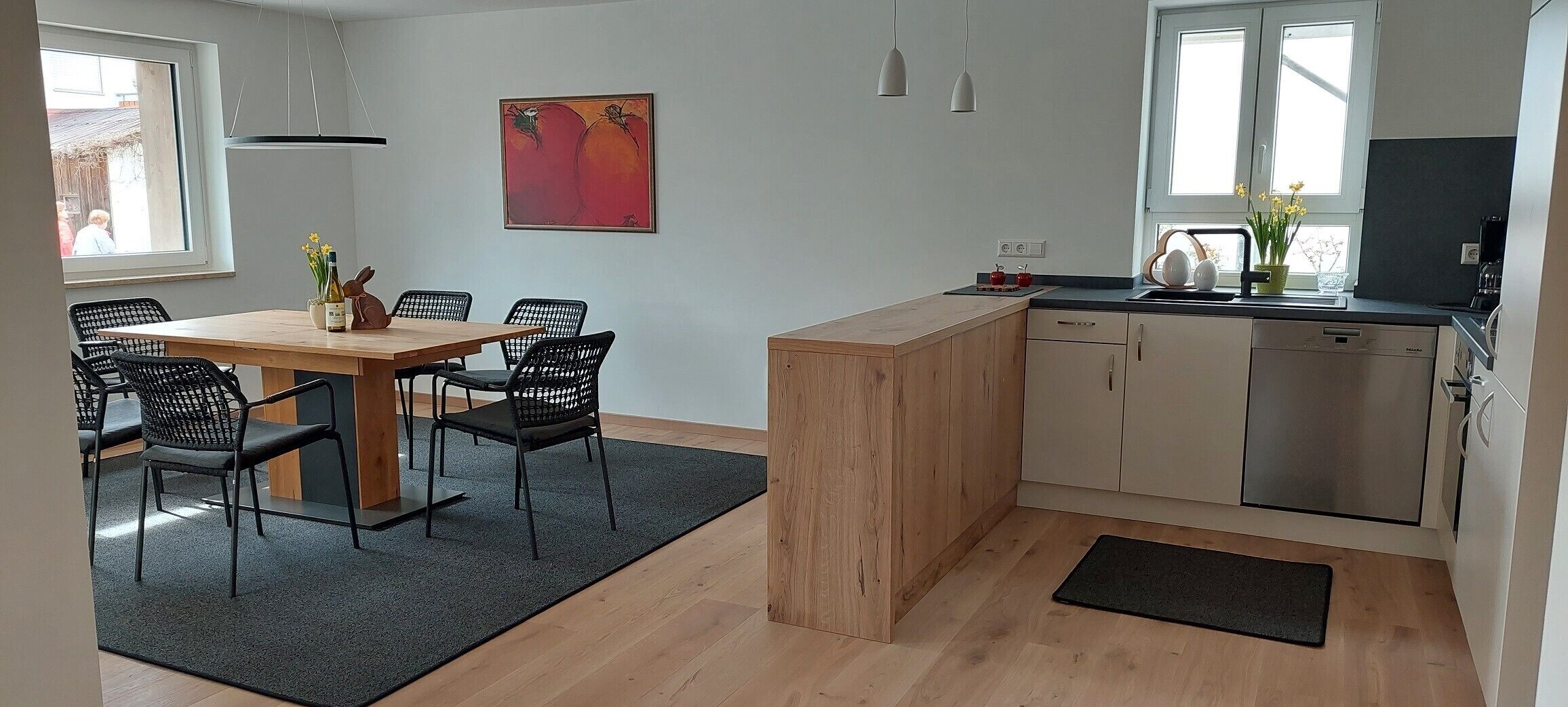 Een compacte keuken met een houten eiland, een zithoek met stoelen en uitzicht op buiten.