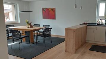 Een compacte keuken met een houten eiland, een zithoek met stoelen en uitzicht op buiten.
