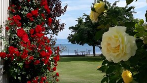 Een tuin met rode en gele bloemen, een grindpad en uitzicht op zee.