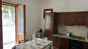 Una cocina compacta con armarios de madera, una estufa a gas y una mesa de comedor con mantel estampado.