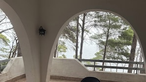Un espacio de estar al aire libre cubierto con una mesa, sillas, una lámpara y vistas a árboles y agua.