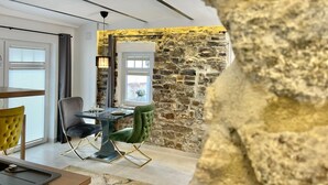 Un comedor con pared de piedra, una mesa con sillas y vistas a través de una ventana.