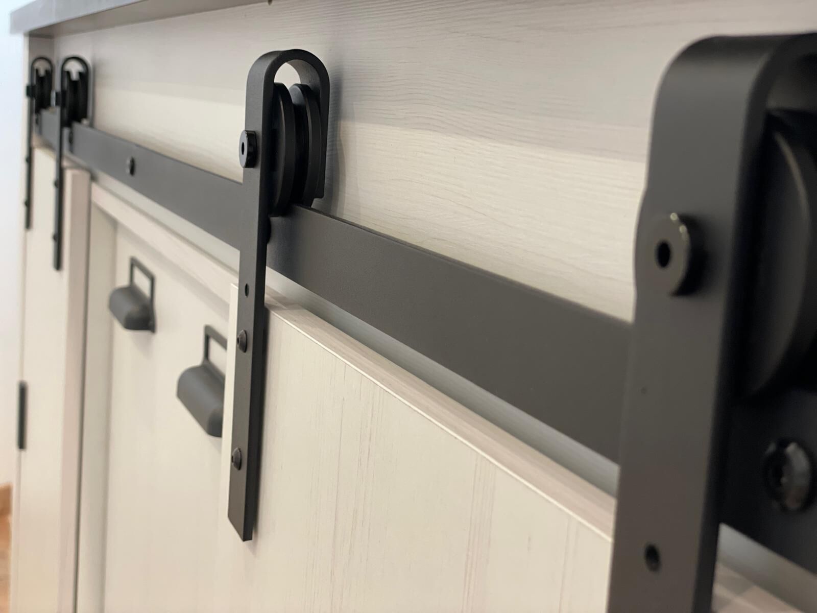 A close-up of a sliding door with a metal track and black hardware.