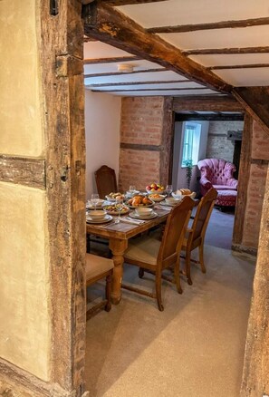 Un comedor con una mesa de madera dispuesta para una comida, rodeado de paredes de ladrillo y un techo inclinado.