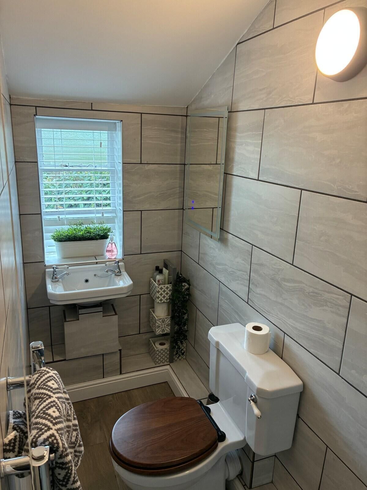A small bathroom with a toilet, sink, and window.