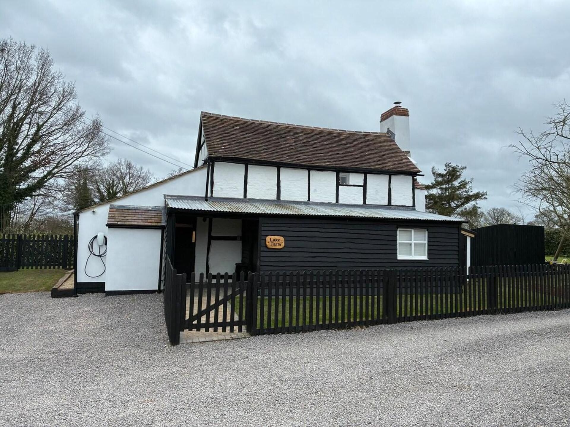 Un bâtiment à deux étages, à l’extérieur noir et blanc, avec une cheminée bien visible et une enseigne indiquant « Lake Farm ».