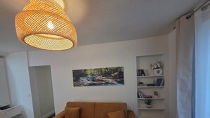 Ein Wohnzimmer mit einer Couch, einer Pendelleuchte, einem Bücherregal und einem Bild von einem Wasserfall.
