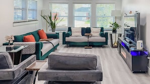Een moderne woonkamer met twee banken, een salontafel, een televisie en een plant.