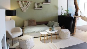 A cozy room with a bed, a chair, a small table, and a hanging plant. - Eulenschlupf, modern and lovely vacation apartment with garden and sauna (Ühlingen-Birkendorf)