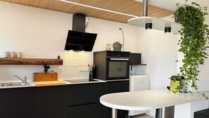 A modern kitchen with a built-in oven, a sink, and a dining area. - Eulenschlupf, modern and lovely vacation apartment with garden and sauna (Ühlingen-Birkendorf)