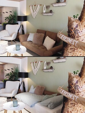 A cozy living room with a brown sofa, white armchair, and a coffee table. There are wall-mounted shelves with decorative items and a sign that reads 'LIEBESNEST'. - Eulenschlupf, modern and lovely vacation apartment with garden and sauna (Ühlingen-Birkendorf)