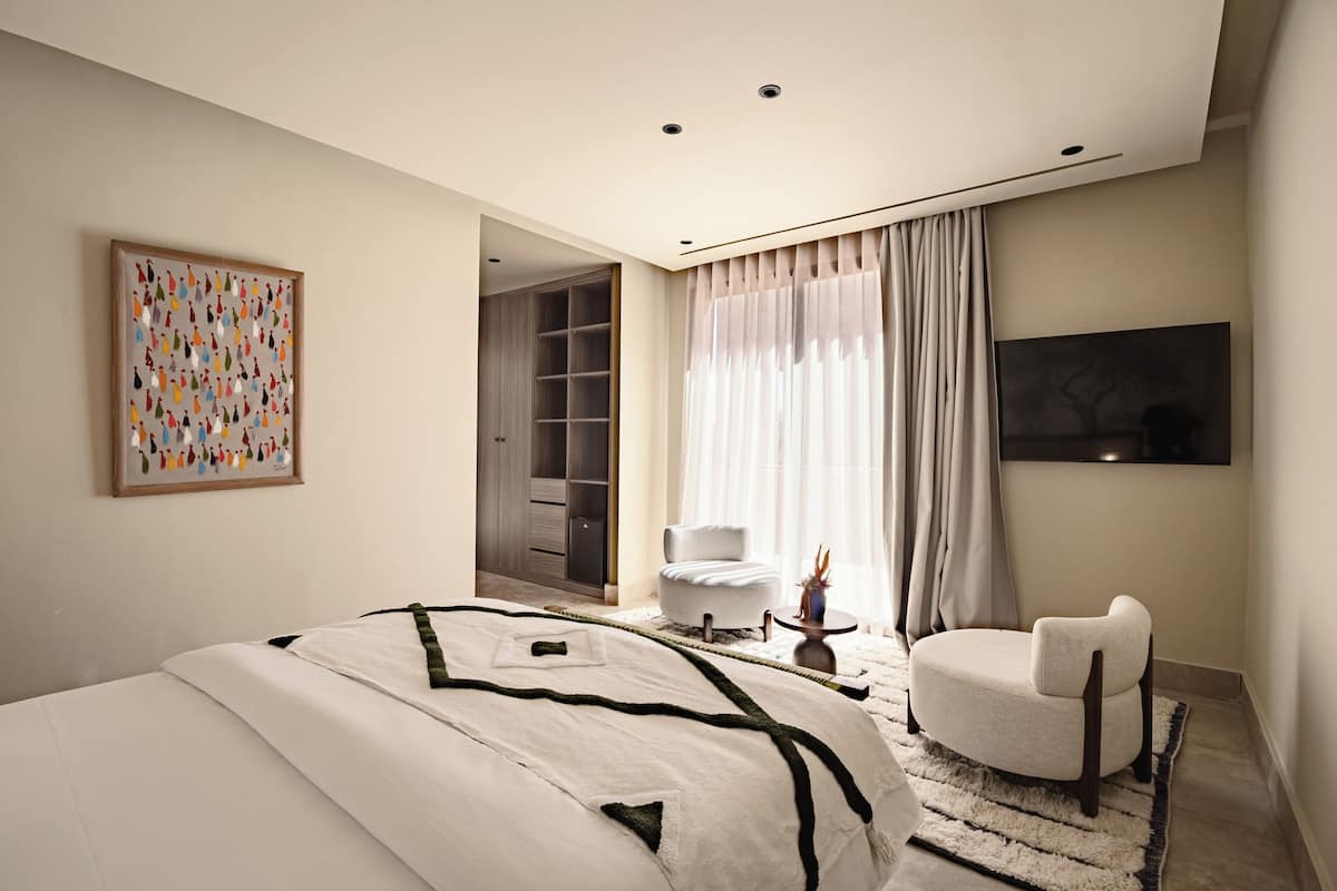 Une chambre moderne avec un grand lit, une chaise, une armoire et un tableau.