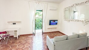 Ein Zimmer mit einer Couch, einem Schreibtisch, einem Fernseher und einem Spiegel.