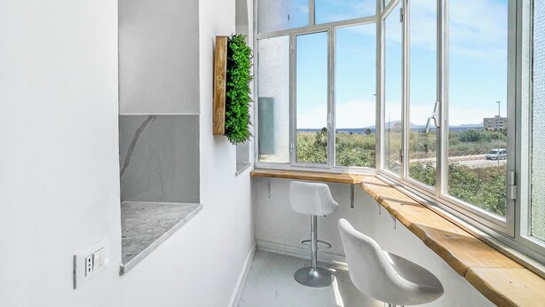 Eine moderne Küche mit einem großen Fenster, einer Holzauslage und zwei Barhocker.