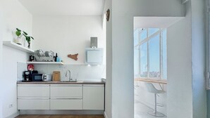 Eine moderne Küche mit weißen Schränken, einer eingebauten Mikrowelle und einer Kaffeemaschine.