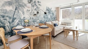 A dining area with a round wooden table, white plates, and glasses, surrounded by wicker chairs. - Cozy Apartment with Balcony | Close to Beach and Station (Gdynia)