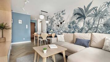 A modern living room with a large mural, a sofa, a dining table, and a coffee table.