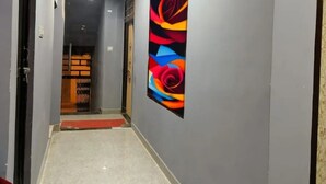 Un couloir au design moderne, agrémenté d’un tableau abstrait aux couleurs vives sur le mur et d’un tapis rouge menant à une porte.