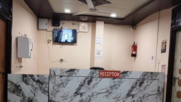 Un espace d’accueil doté d’un comptoir en marbre, d’un ventilateur de plafond, d’un téléviseur et d’un extincteur.