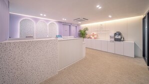 Un espace d’accueil au design moderne, comprenant un comptoir de réception, une plante et un panneau fixé au mur.