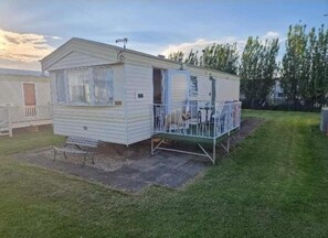 A mobile home with a fenced porch and a small patio area. - Caravan in Chapel , Skegness (Skegness)