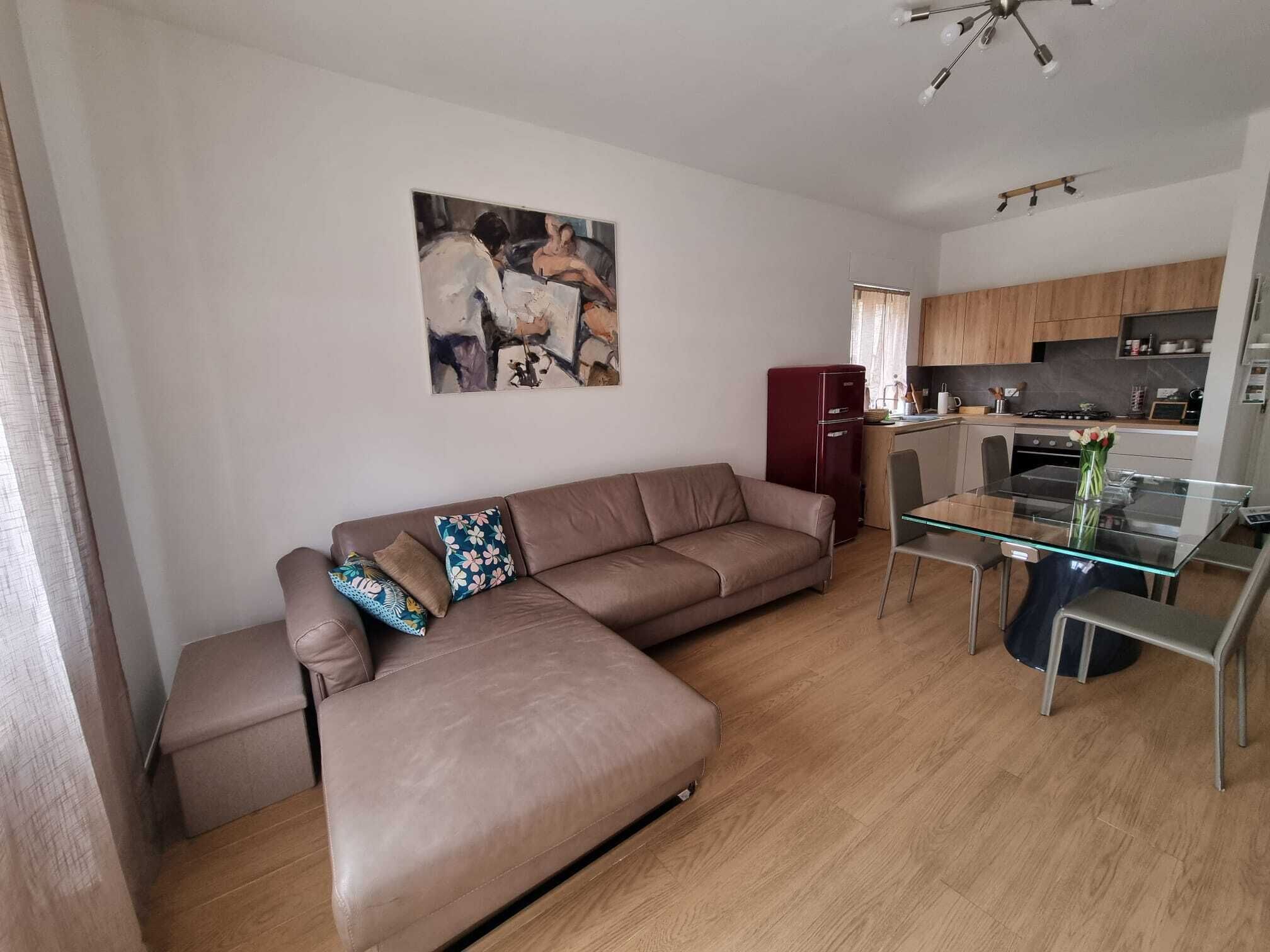 A living room with a sofa, a glass coffee table, and a painting on the wall.