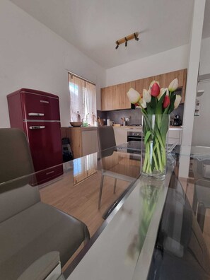 Una cucina moderna con mobili in legno, un frigorifero rosso e un tavolo da pranzo in vetro.