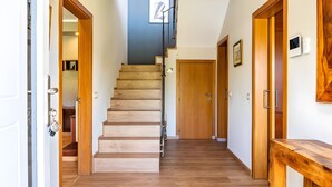 Escada de madeira que leva a um segundo andar, uma porta de madeira e um banco de madeira.