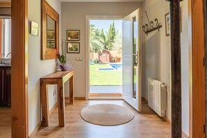 A hallway with a wooden bench, a round rug, and a door leading to a backyard with a pool. - Casa Monica – Charming House with Garden and Pool Near the Village Center (Calonge)