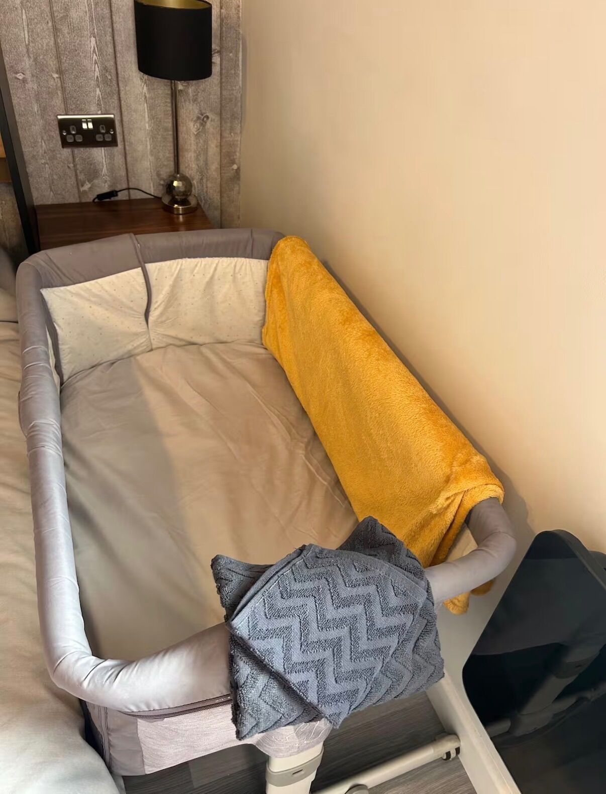 Un lit avec un matelas gris, une serviette jaune et un oreiller gris à motifs.