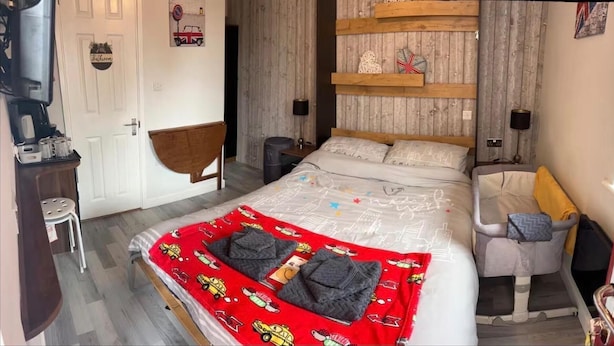 A bedroom with a bed, a chair, a desk, and a door.