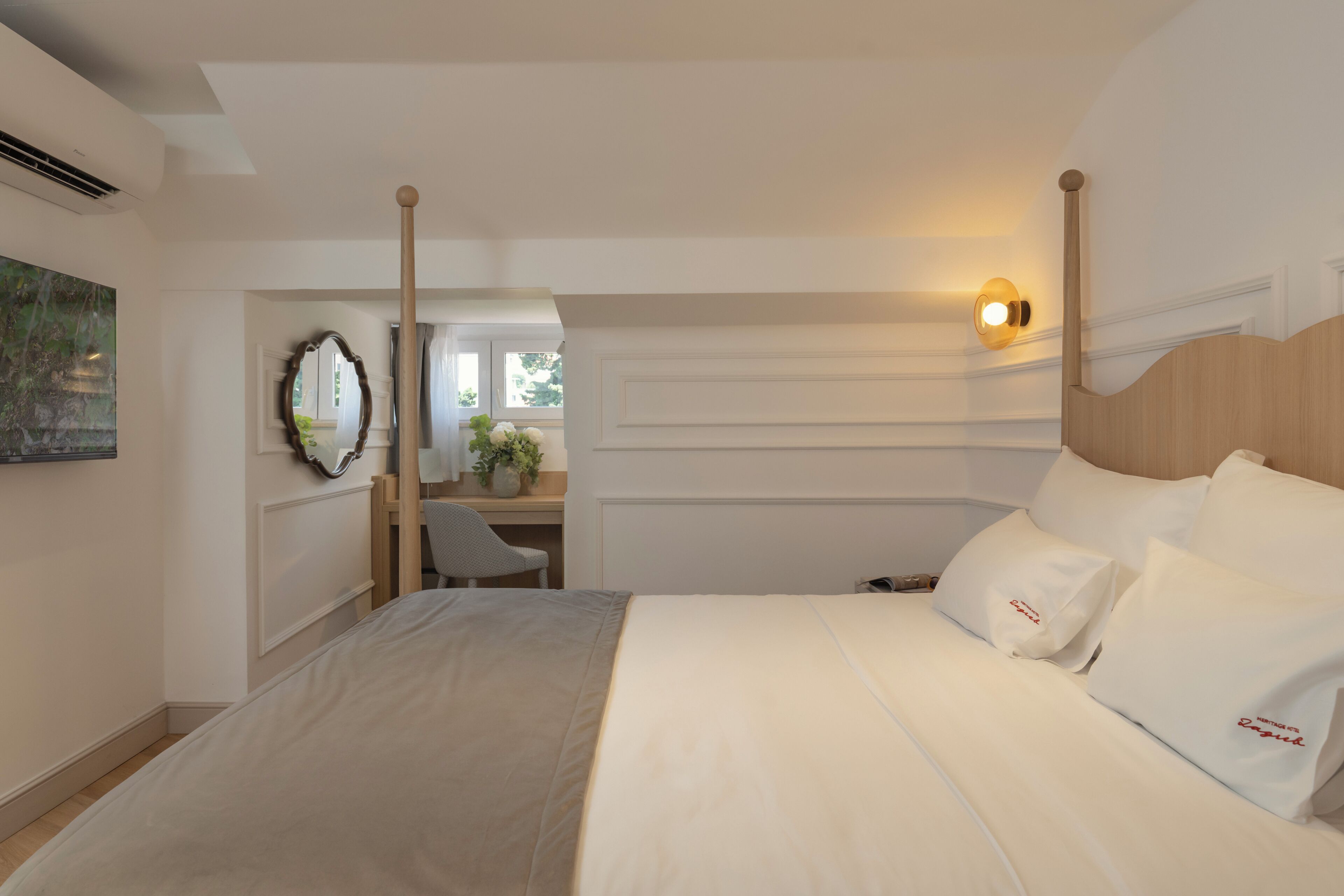 A hotel room with a large bed, a desk, and a chair.