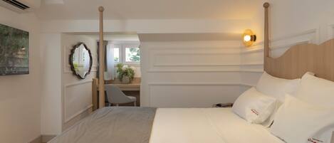 A hotel room with a large bed, a desk, and a chair.