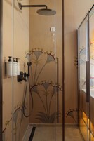 Una ducha con puerta de vidrio, cabezal de ducha de mano y panel de control en la pared.