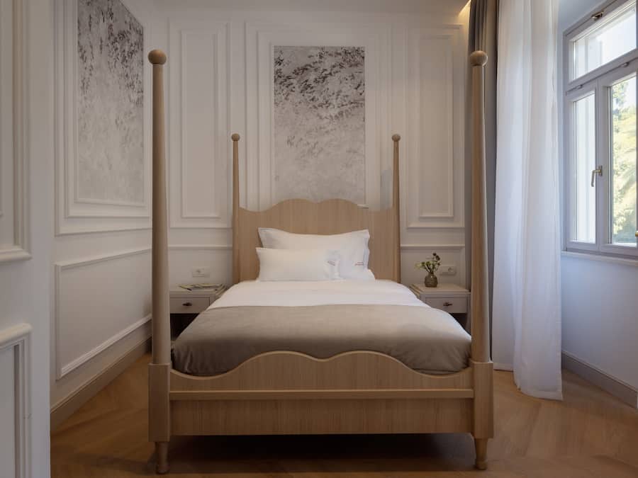 A four-poster bed in a room with white walls and a wooden floor.