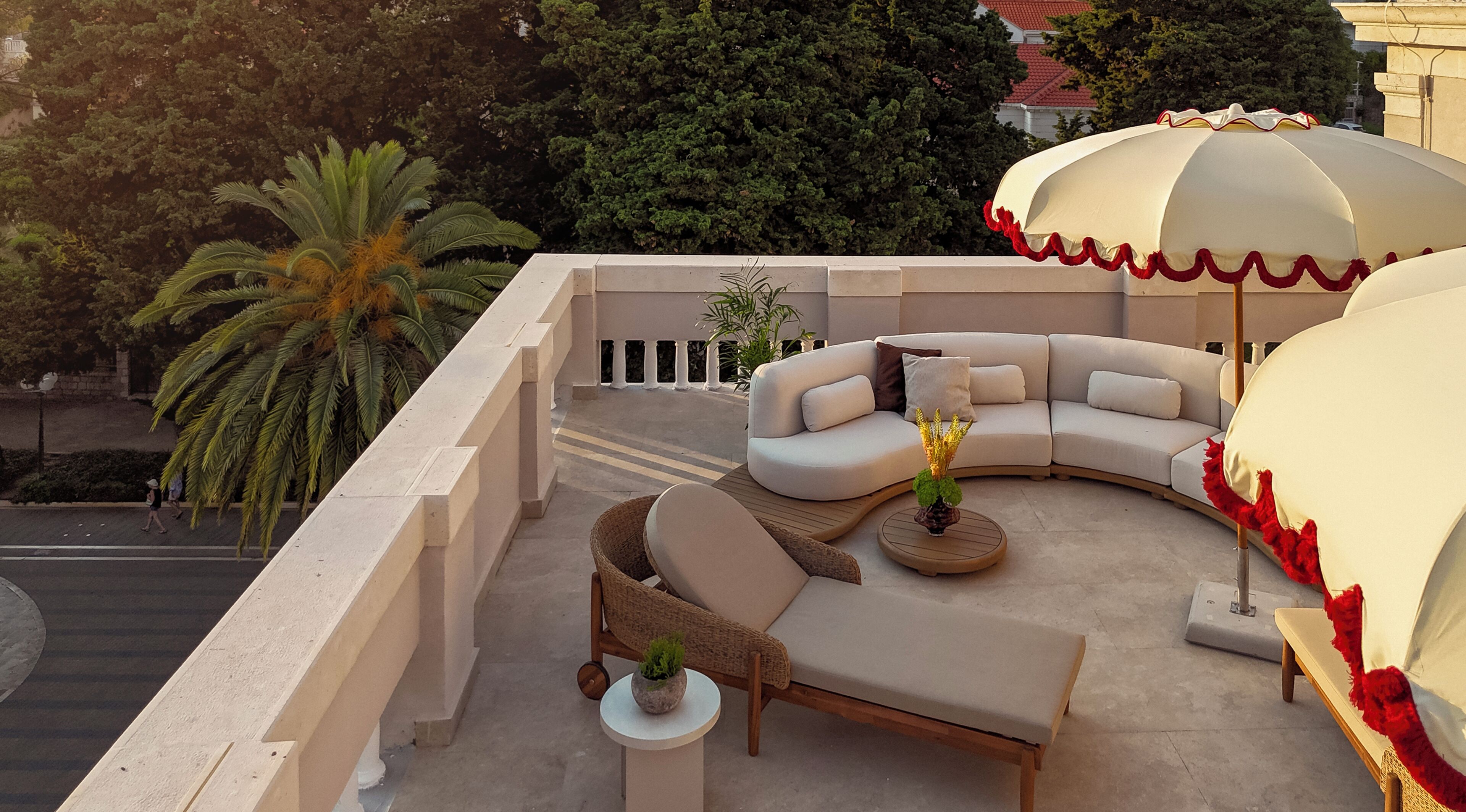 Una terraza en la azotea con un sofá curvo, una mesita redonda y una planta en maceta.